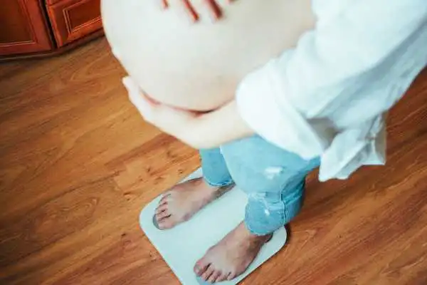 Image of woman weighing herself and experiencing weight gain through pregnancy Hythe